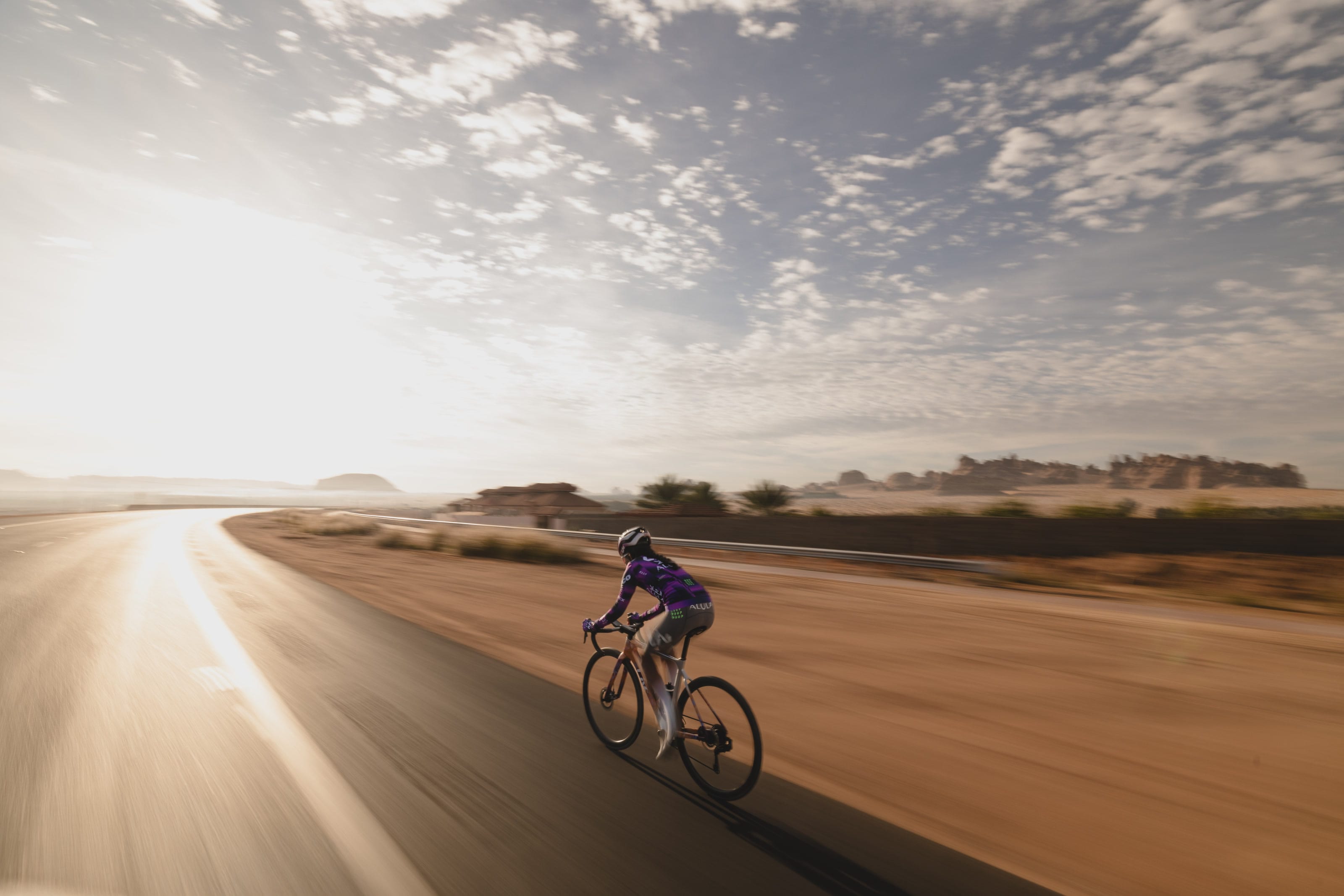 Moroj Adil riding alone on a desert road under a wide morning sky