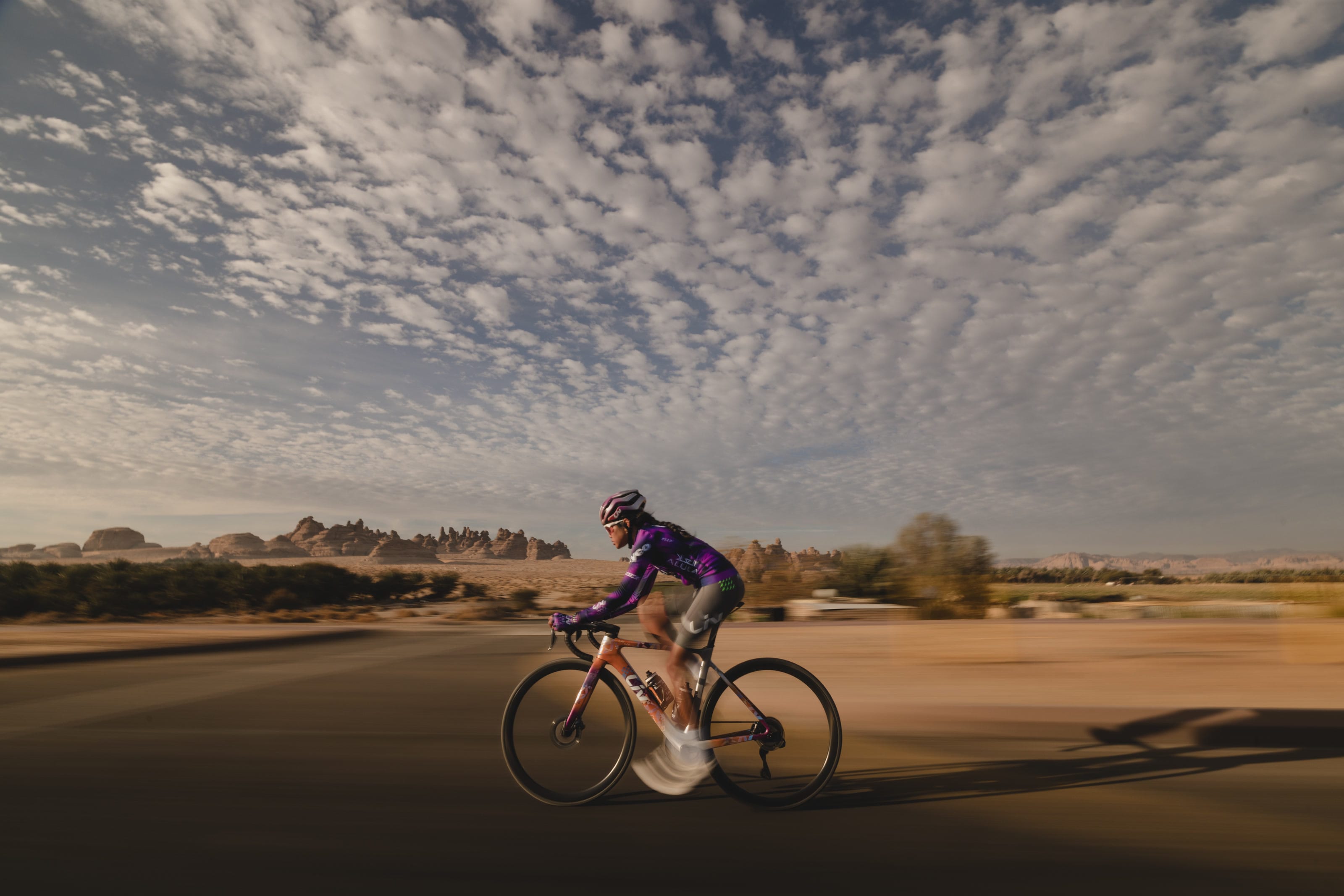 Moroj Adil riding at speed past the rock formations of AlUla in low sun